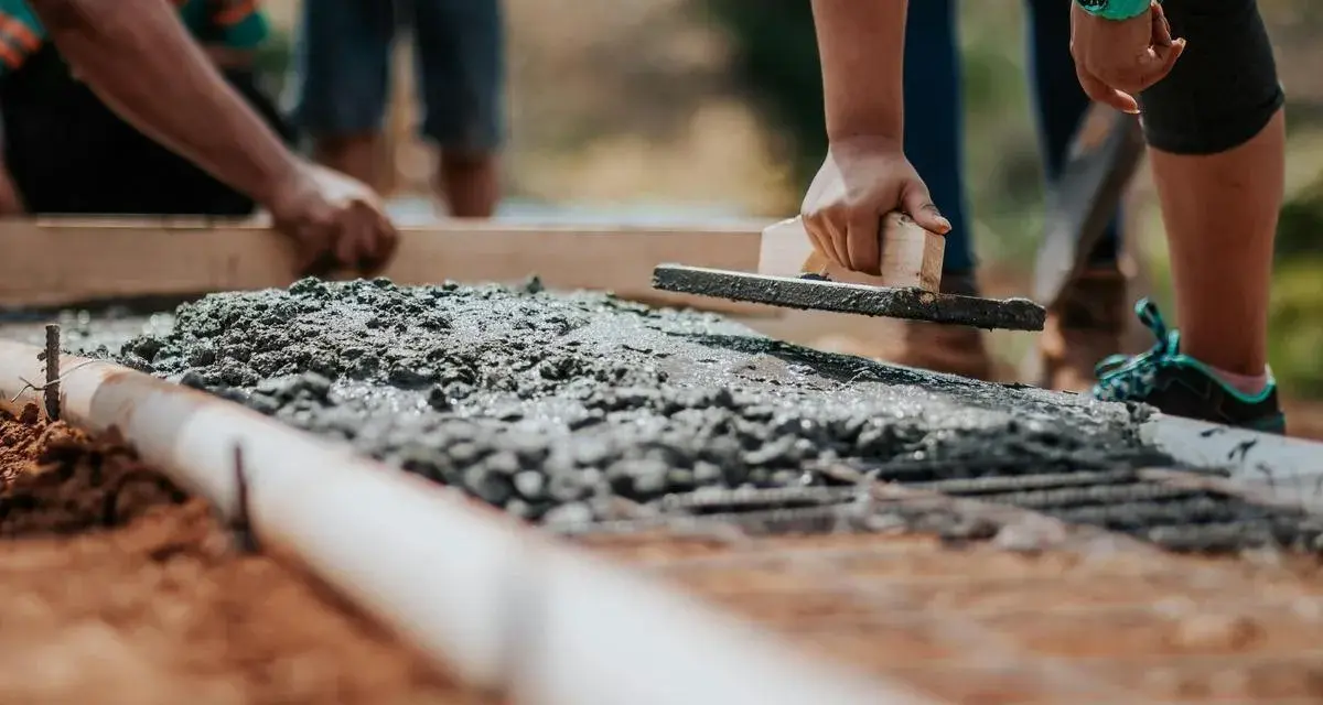 Pracownicy wyrównują świeży beton na fundamencie. Jaki beton na fundament b20 czy b25?