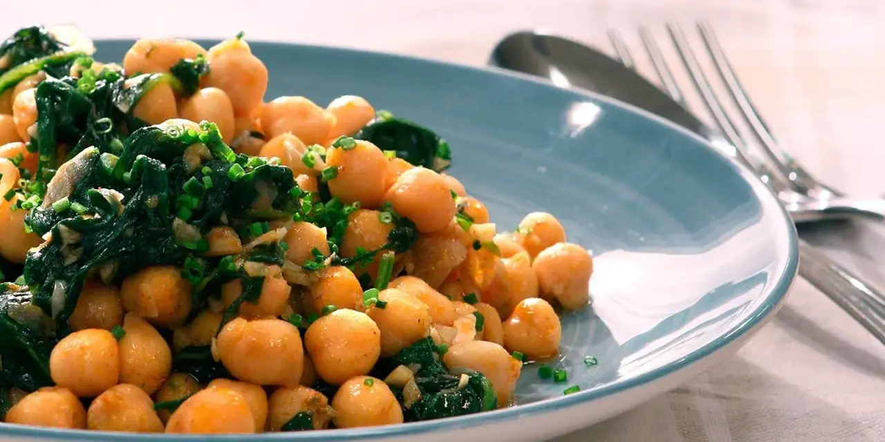 Garbanzos salteados con espinacas y ajo, una de las muchas recetas con garbanzos de bote, servidos en plato azul.