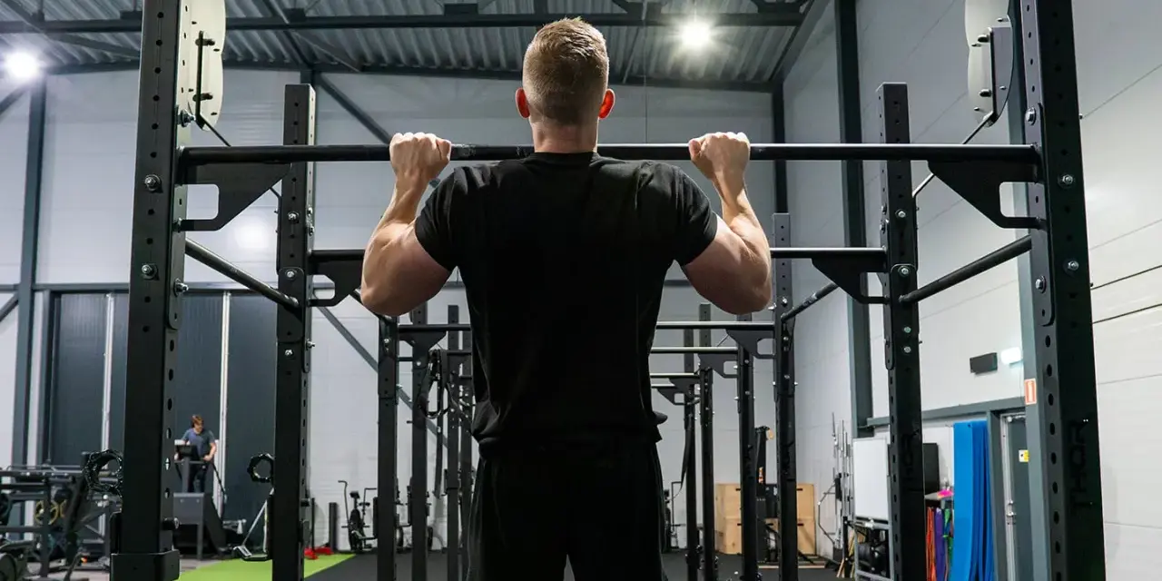 Man tränar pull ups i ett modernt gym.