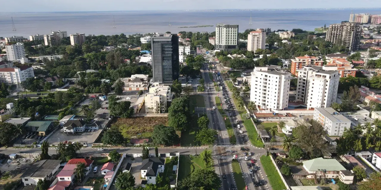 Widok z lotu ptaka na nowoczesne miasta w Afryce, z wysokimi budynkami, zielenią i ruchliwą drogą w tle.