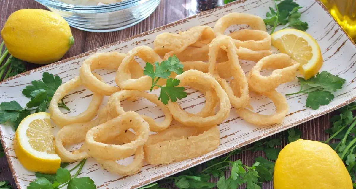 Calamares a la andaluza crujientes y dorados, servidos con limones frescos y perejil.