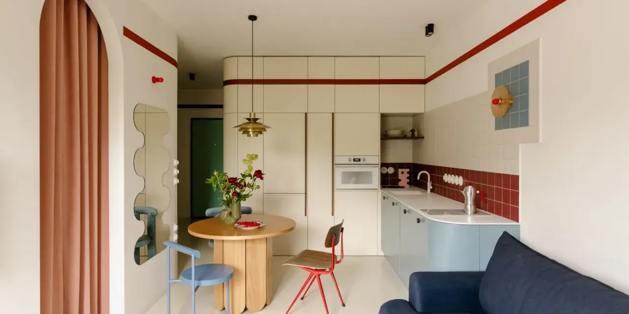 Un angolo di casa moderna con richiami alle case tipiche italiane: un tavolo rotondo, sedie colorate e una cucina funzionale.