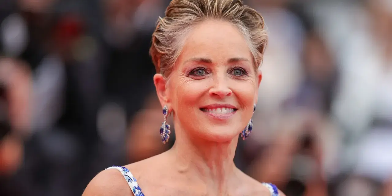 Sharon Stone luce un elegante corte bixie, con pendientes de zafiro y un vestido blanco con detalles azules.