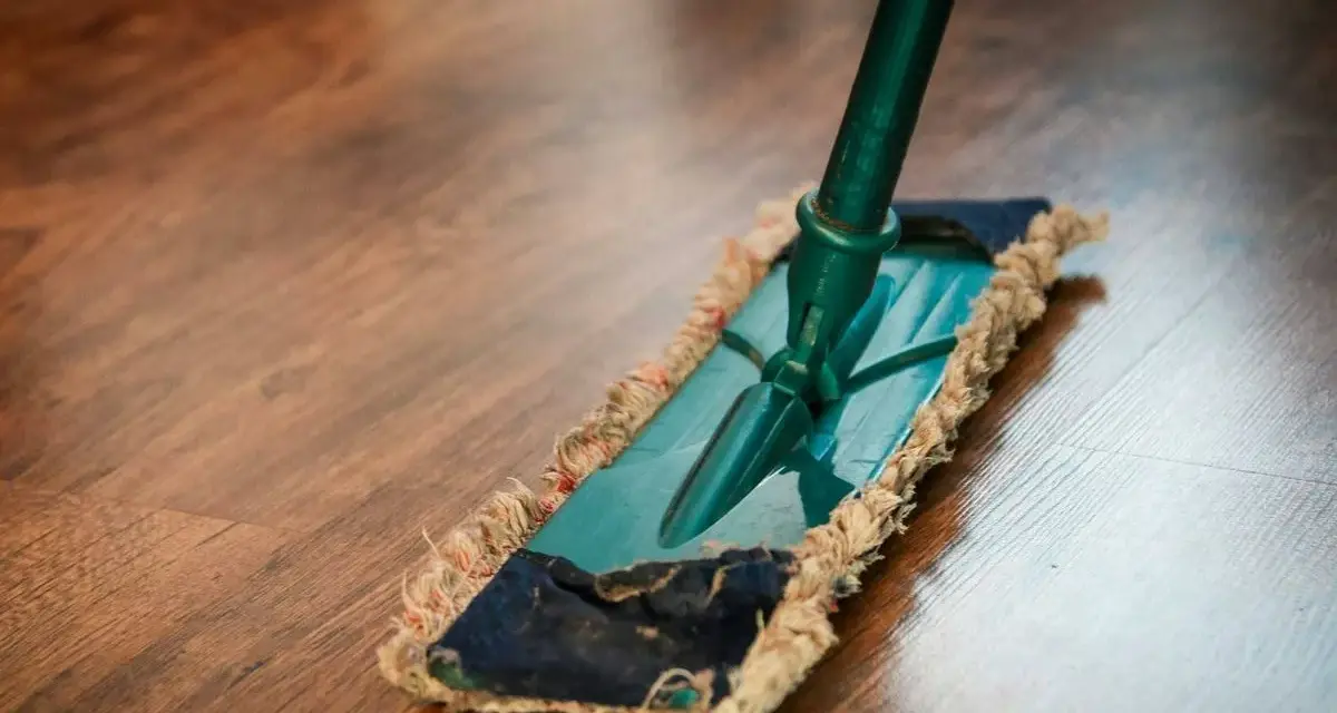 Mopa limpiando un suelo de parquet. Descubre remedios caseros para reparar parquet y mantenerlo como nuevo.