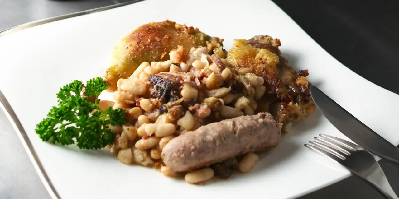 Un plato de el cassoulet con pollo crujiente, salchicha y perejil fresco.