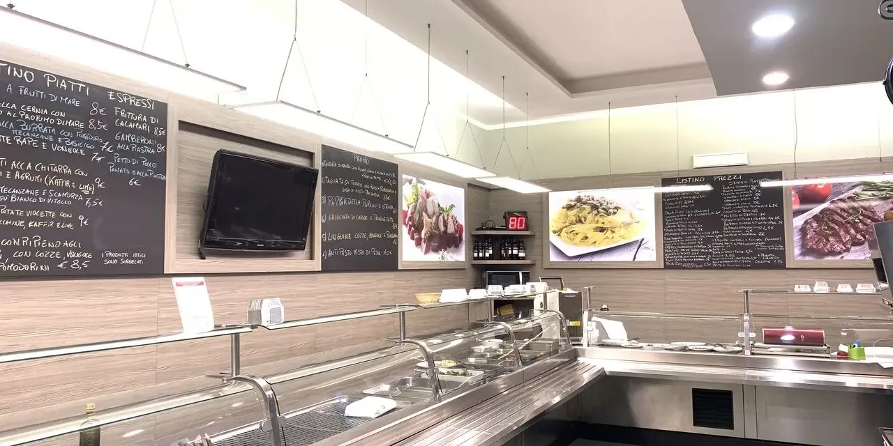 Interior of a restaurant with a display counter, menu boards, and food images.