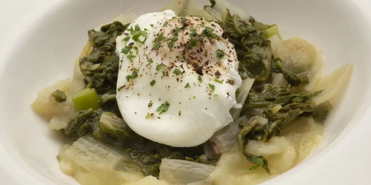 Huevo escalfado sobre pencas de acelgas guisadas, con perejil picado y pimienta. Un plato sencillo y nutritivo.