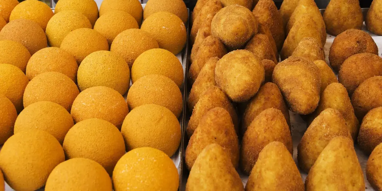 Arancini e arancine dorati, pronti per essere gustati. Un tripudio di sapori siciliani.