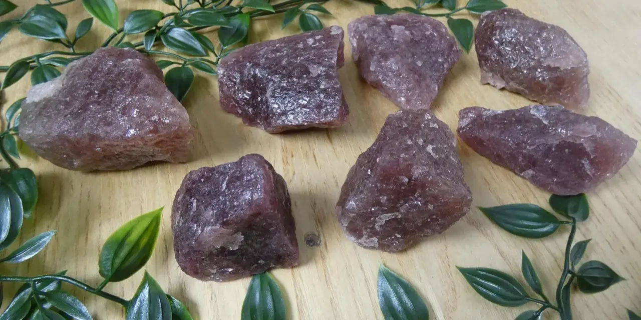 Gruppo di quarzo fragola grezzo su fondo di legno. Le sue proprietà sono note per favorire l'amore e la guarigione emotiva.