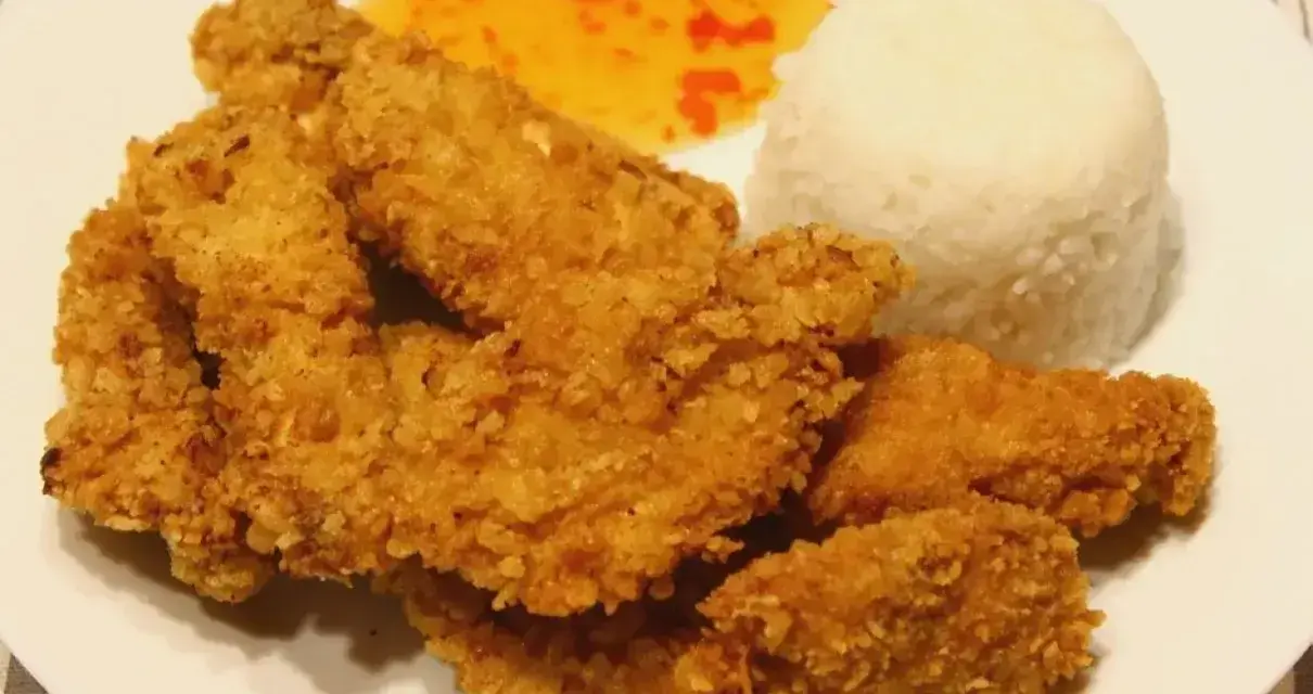 Chrupiący kurczak w panko, ryż i słodko-kwaśny sos na białym talerzu.