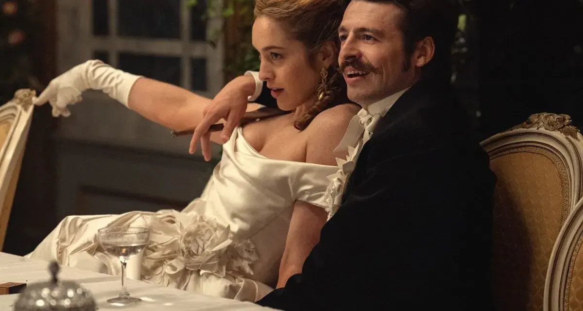 Elegancka para przy stole, zapowiedź nowych produkcji Netflix. Kobieta w białej sukni z rękawiczkami, mężczyzna w czarnym fraku.