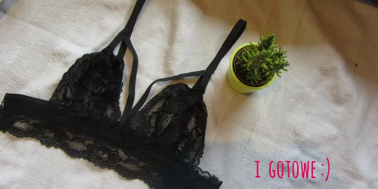 Czarny, koronkowy biustonosz typu bralette, idealny do obszywania bielizny. Obok mała roślinka w doniczce.