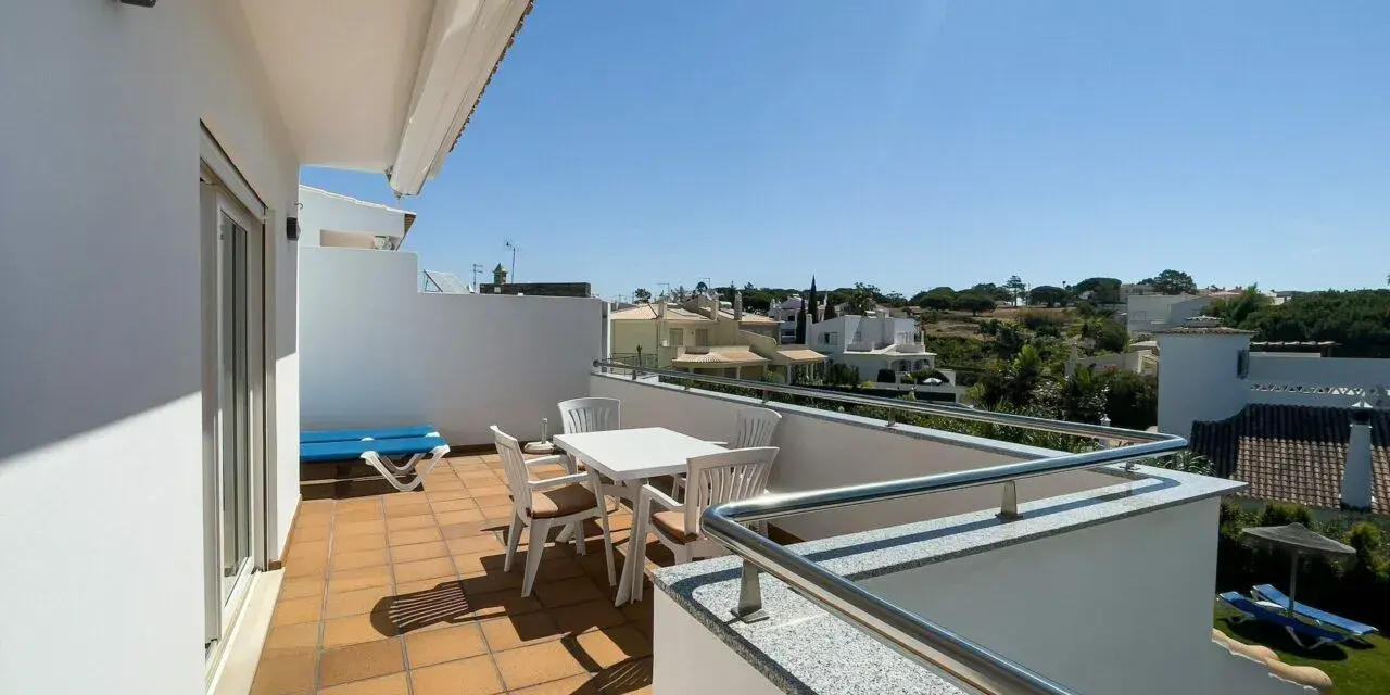 Słoneczny balkon z meblami i widokiem na domki. Idealne miejsce na poranną kawę i planowanie dnia.