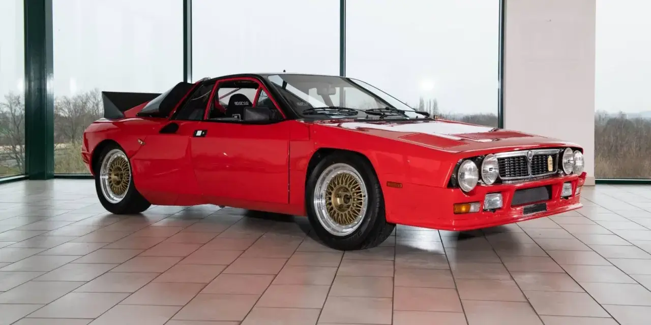 Czerwona Lancia 037 z czarnym spojlerem i złotymi felgami, gotowa do rajdu.