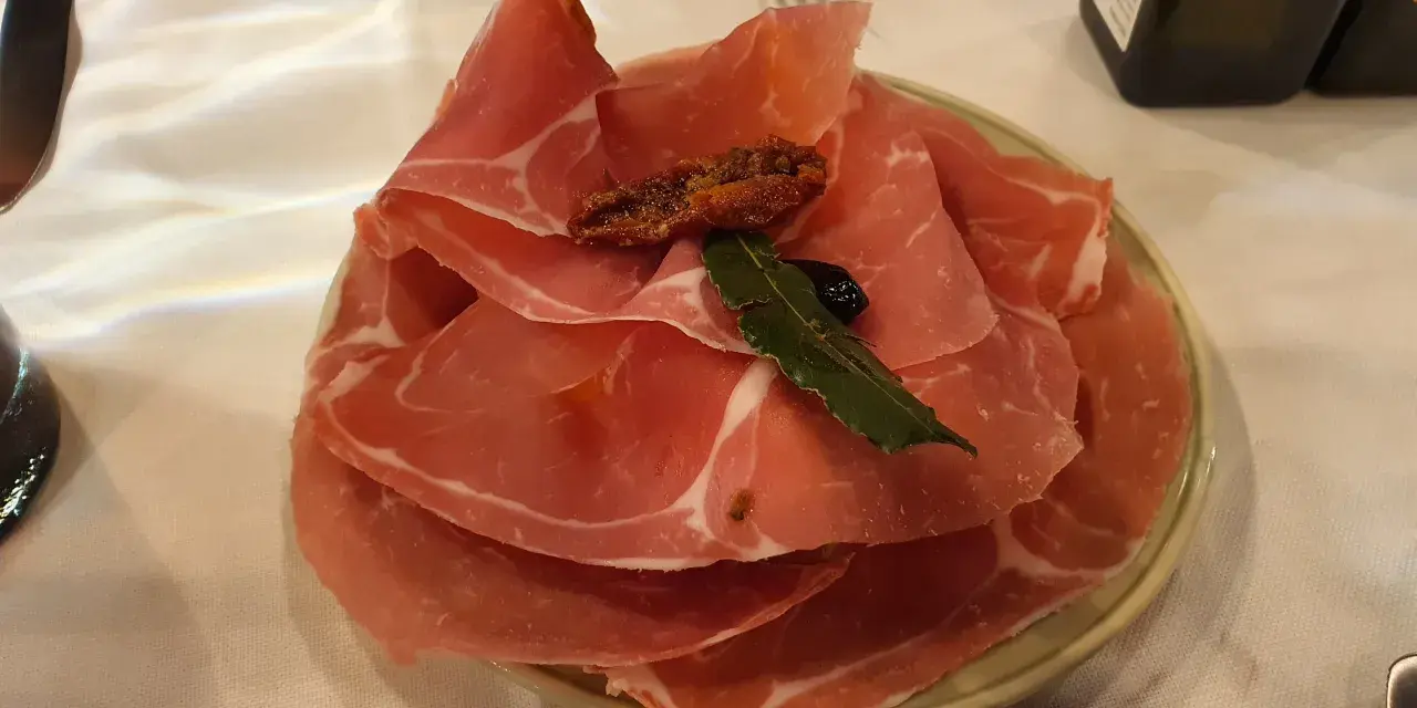 Plastry prosciutto na talerzu, idealne na przystawkę we Florencji. Co zjeść? Prosciutto to świetny wybór!