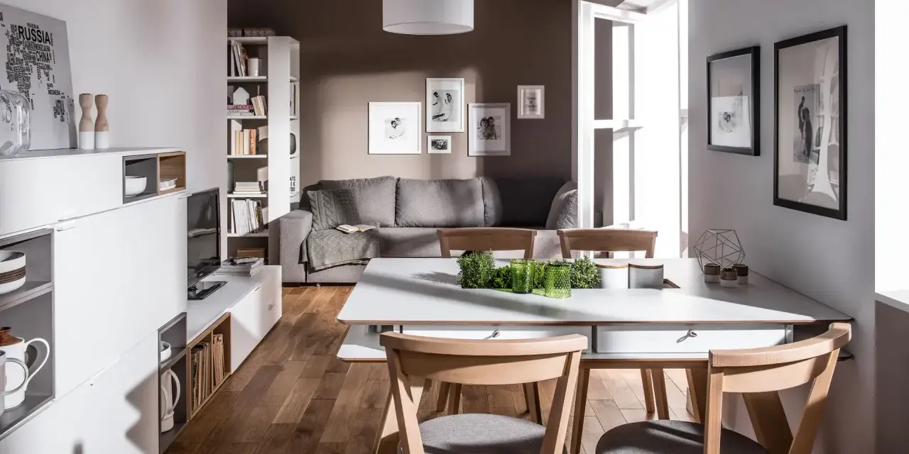 Nowoczesny salon z szarą kanapą i drewnianymi krzesłami. Czy brązowy pasuje do szarego? Tak, w tej aranżacji tworzy przytulną atmosferę.