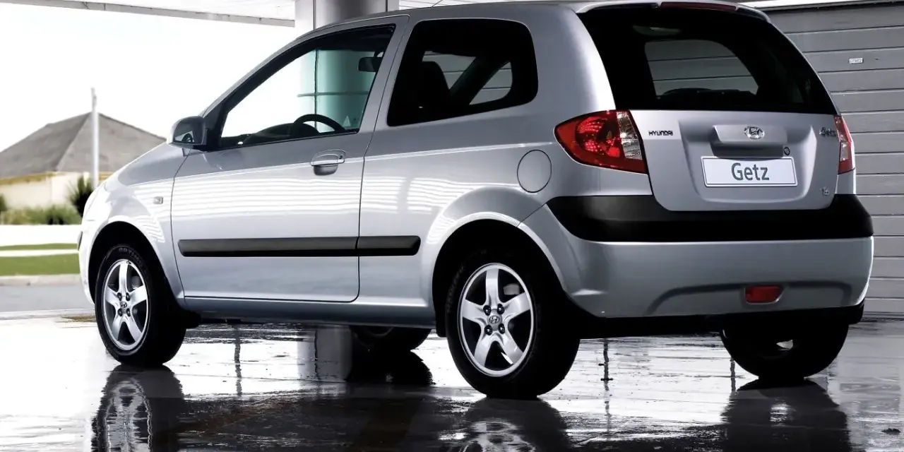 Srebrny Hyundai Getz 1.1 z czarnymi listwami, odbijający się w mokrej nawierzchni pod zadaszeniem.
