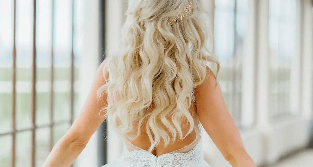 Długie, falowane blond włosy ozdobione złotą spinką. Fryzura w stylu lat 20. idealna na ślub.