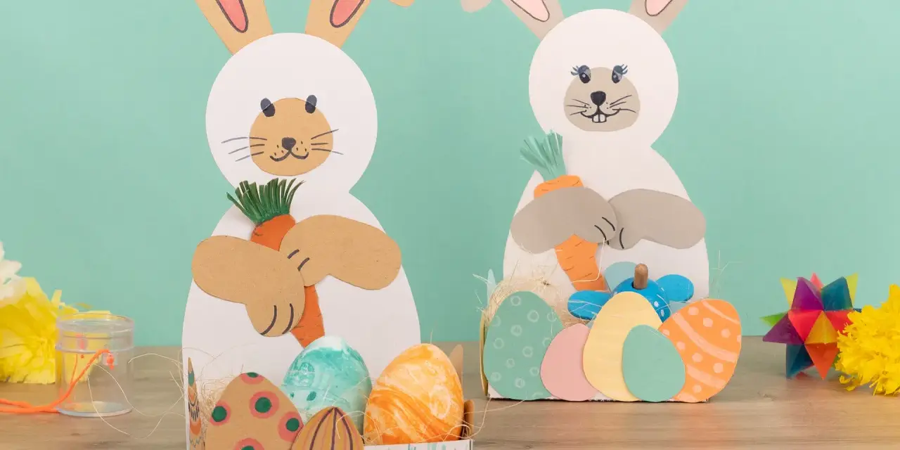 Zwei süße Osterhasen halten Karotten. Kinder haben diese tollen Osterdeko zum Thema Osternest basteln Kinder selbst gemacht.
