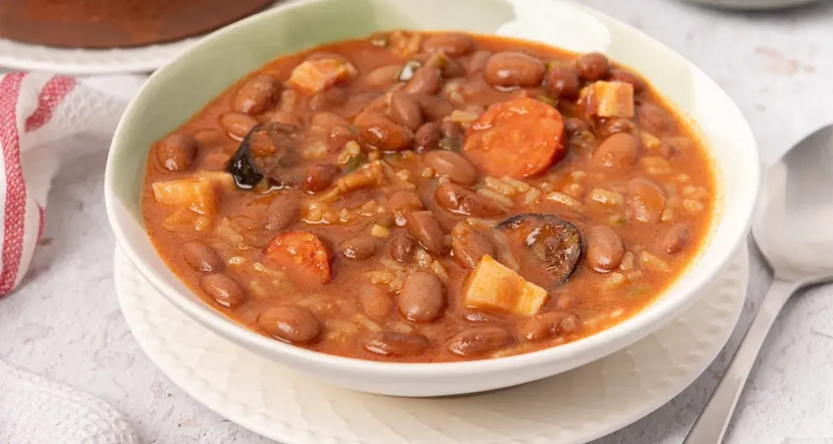 Un tazón de judías pintas con chorizo, patatas y arroz en un guiso meloso.