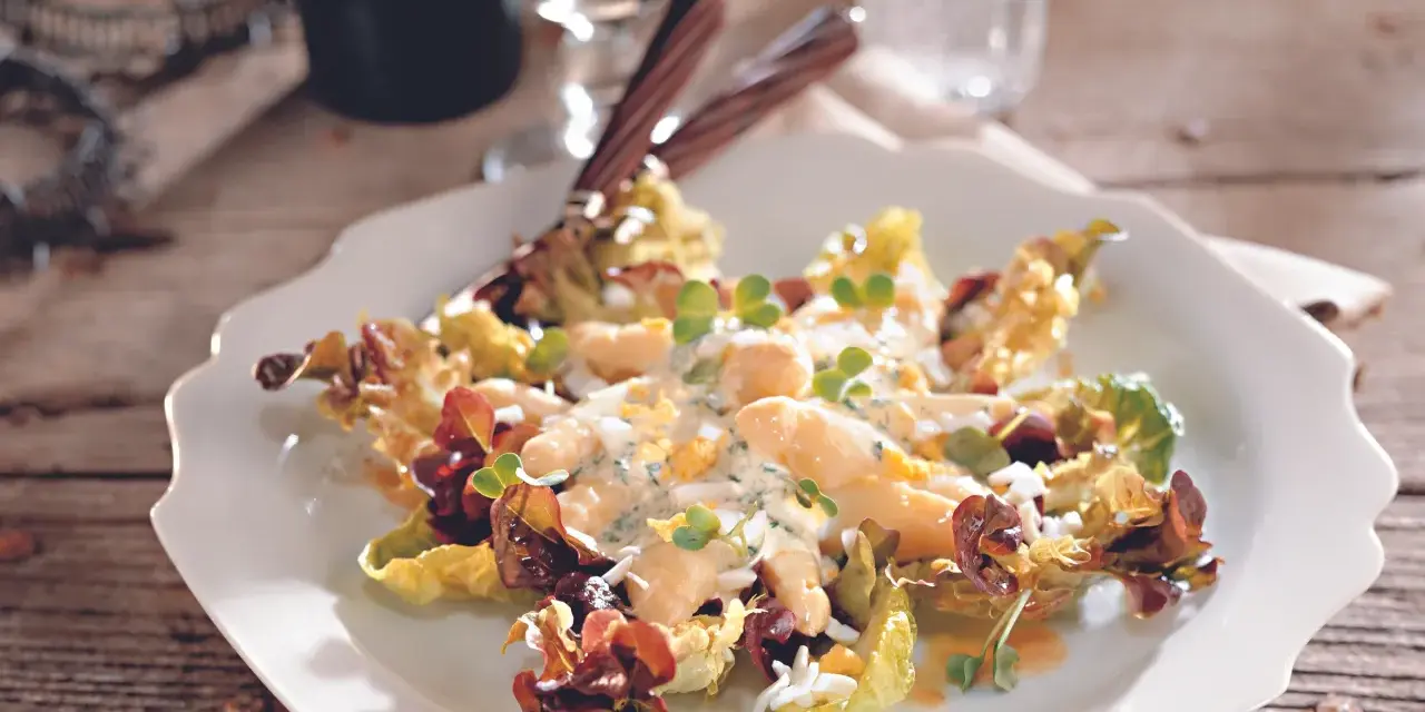 Omas Spargelsalat mit cremigem Dressing, Eiern und Kräutern, serviert auf einem weißen Teller mit Salatblättern.