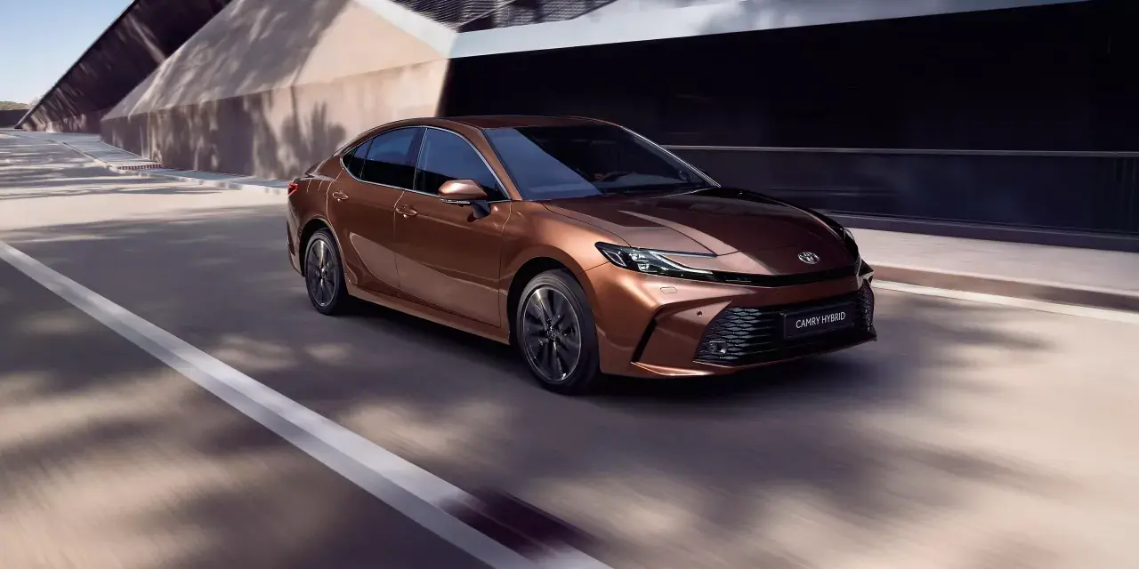 Brązowa Toyota Camry Hybrid w ruchu. Sprawdź aktualną toyota camry cena i wybierz swój wymarzony model.