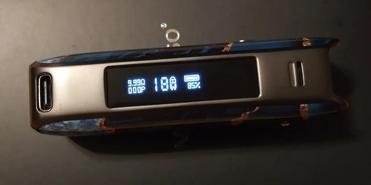 Vaporesso Luxe PM40 con pantalla mostrando 18W y 85% de batería. Diseño con detalles azules y marrones.