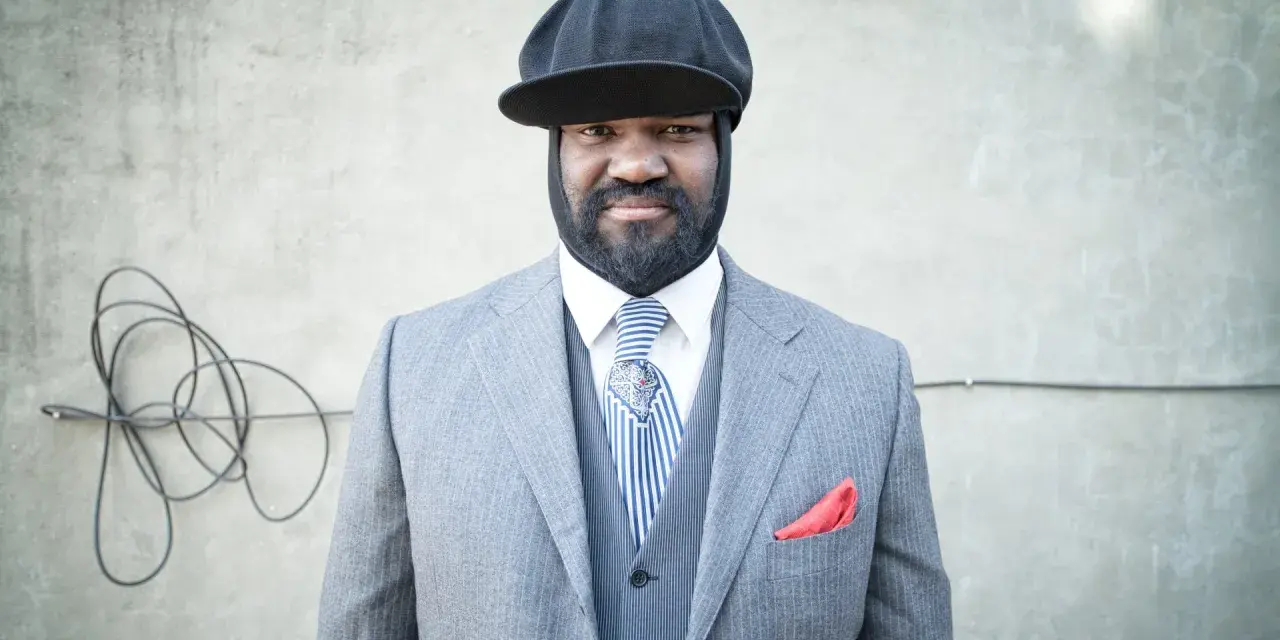 Gregory Porter w eleganckim garniturze i czapce, gotowy na koncert.