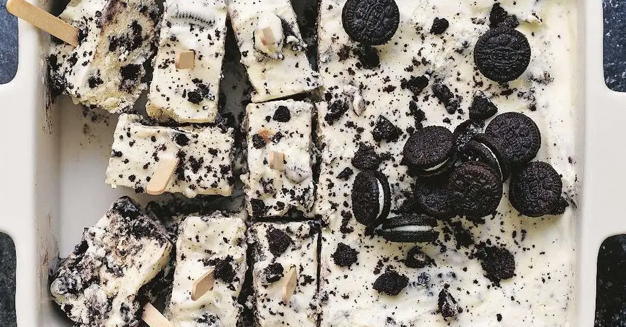 Oreo glass recept: krämig glass med krossade Oreos och hela kakor, skuren i bitar med träpinnar. Perfekt sommardessert!