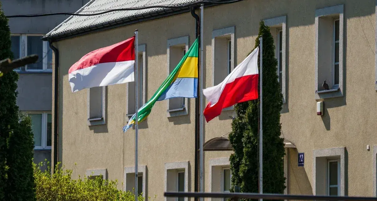 Trzy flagi powiewają przed budynkiem: biało-czerwona flaga Polski, flaga Monako (identyczna jak Indonezji) i flaga Gabonu.