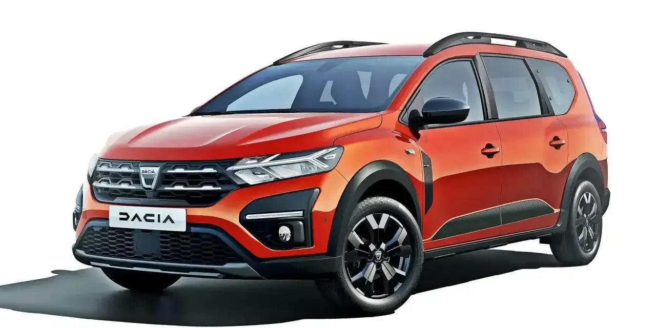 Pomarańczowy Dacia Jogger, marka samochodu na d, z relingami dachowymi i czarnymi felgami.