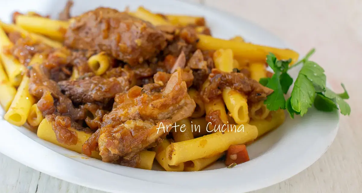 Piatto di ziti alla genovese con ragù di carne e cipolle caramellate, guarnito con prezzemolo fresco.