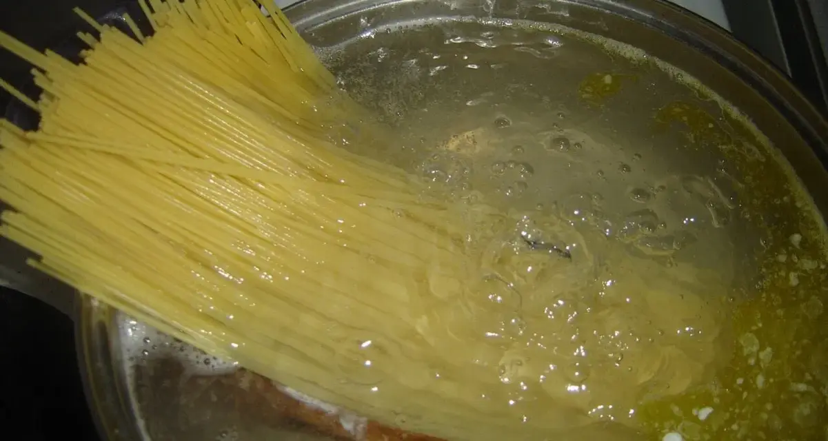 Długi makaron spaghetti gotuje się w bulgoczącej wodzie. Czas, **ile gotować makaron**, zależy od jego grubości.