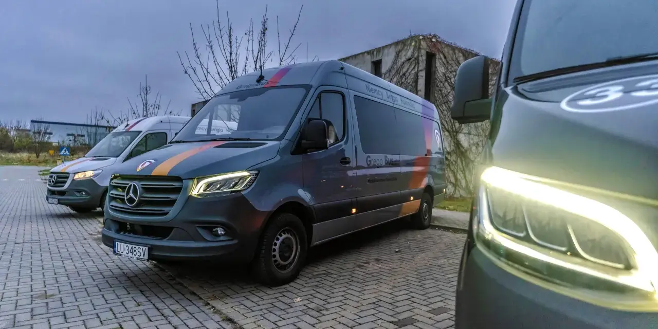 Busy Chełm Zamość przez Krasnystaw. Kilka busów "Grego Bus" zaparkowanych na kostce brukowej, gotowych do podróży.