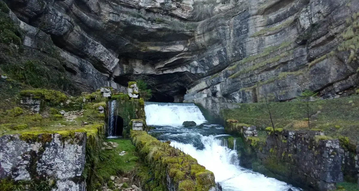 La source de la Loue, un spectacle naturel impressionnant. L'itinéraire mène à travers ce paysage rocheux où l'eau jaillit d'une grotte.