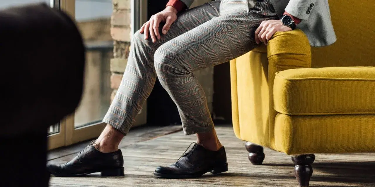 Eleganckie, ciemnobrązowe buty męskie do szarego garnituru w kratę. Stylizacja idealna na co dzień i specjalne okazje.