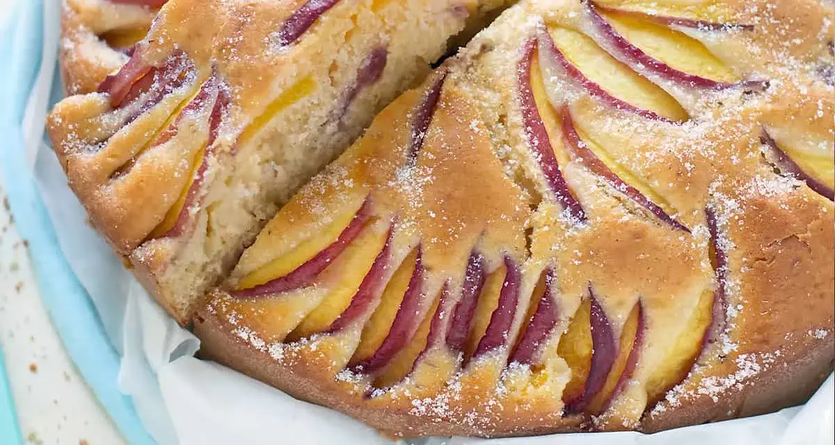 Torta di pesche velocissima, soffice e profumata, con fette di pesca disposte a raggiera sulla superficie dorata.