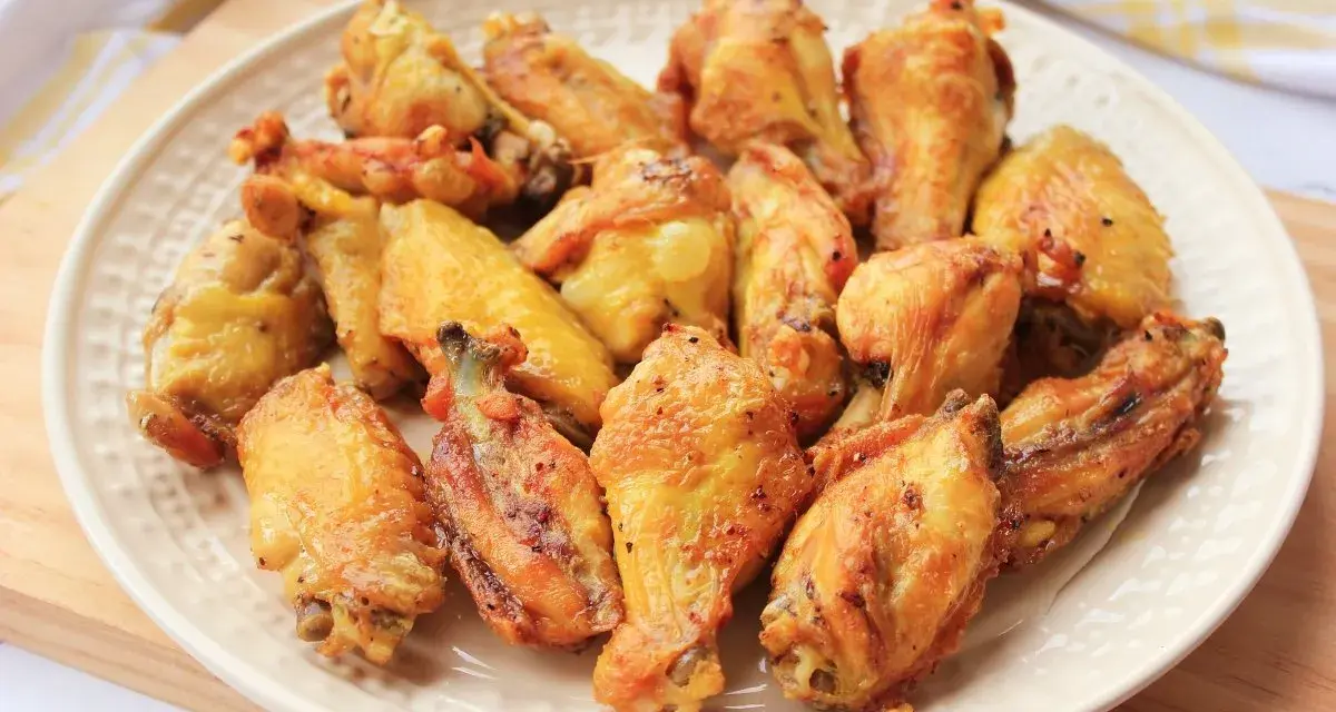 Alitas de pollo doradas y crujientes en un plato blanco.
