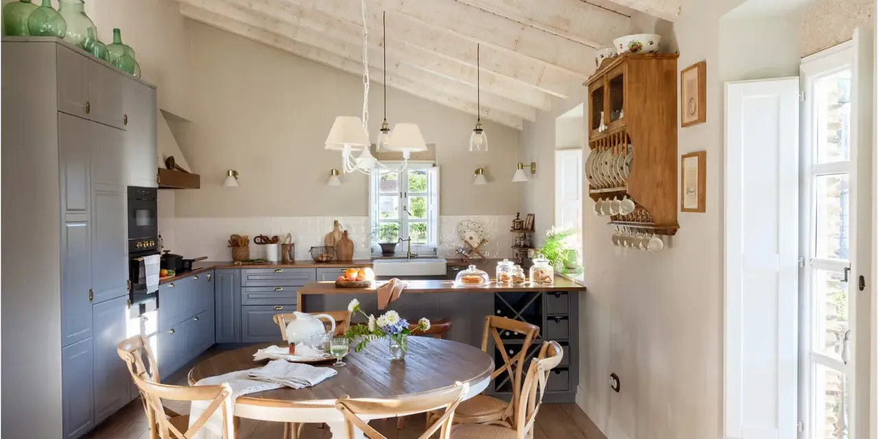 Cocina rústica y acogedora. Ideas para decorar casa vieja de pueblo con poco dinero. Techos de madera, muebles grises y mesa redonda.