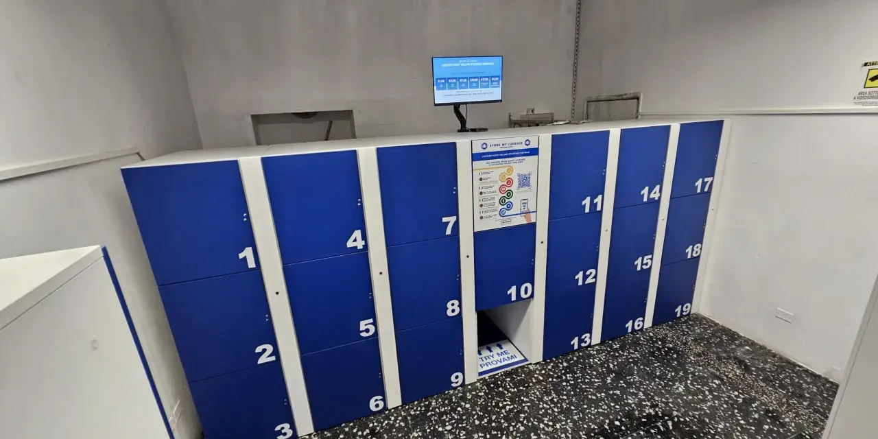 Blue and white numbered luggage lockers with a digital screen and instructions.