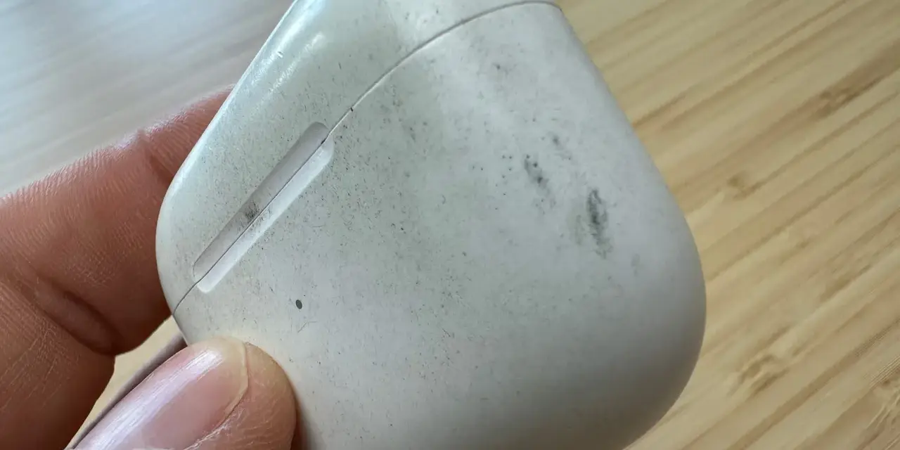 Eine schmutzige weiße Hülle für AirPods wird von einer Hand gehalten.