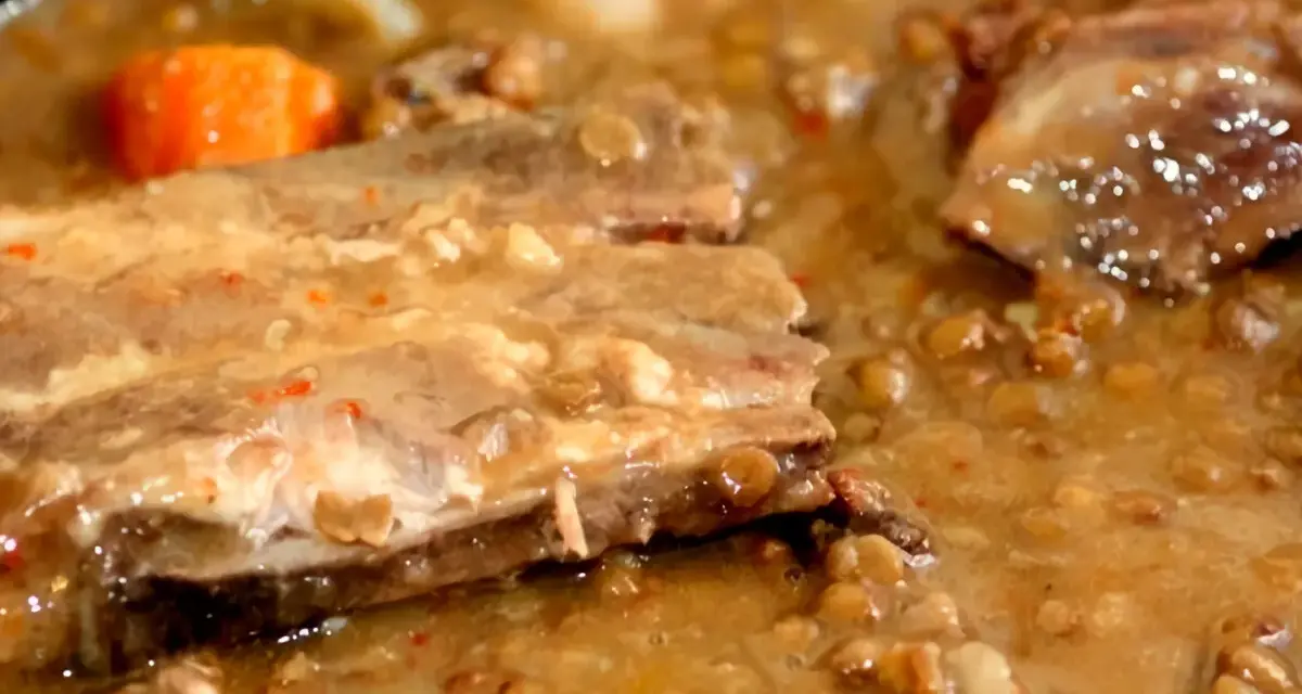 Guiso de lentejas con costillas, zanahoria y trozos de carne en un caldo espeso.
