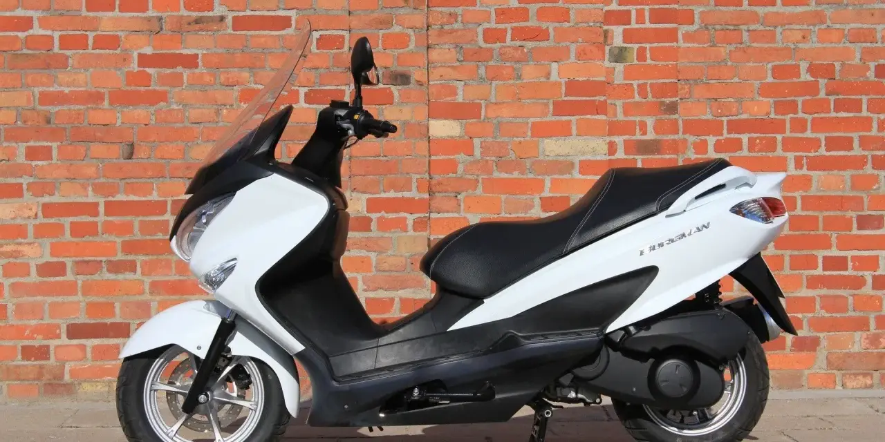 Biały skuter Suzuki Burgman 125, idealny do miasta, z niskim spalaniem.