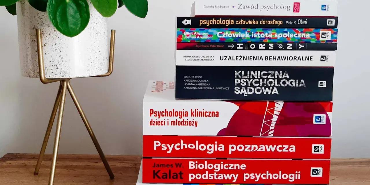 Stos książek do studiów psychologicznych, od psychologii społecznej po kliniczną, obok rośliny w doniczce.