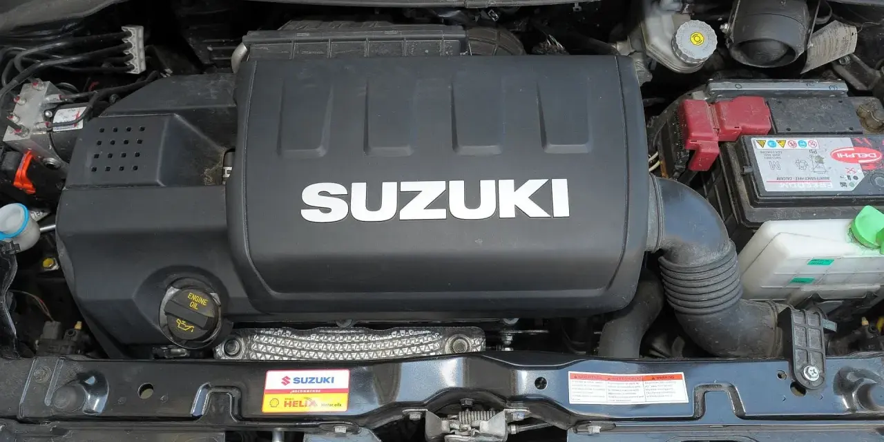 Silnik Suzuki Swift 2007 z widocznym logo SUZUKI na pokrywie. Widać akumulator i elementy układu dolotowego.