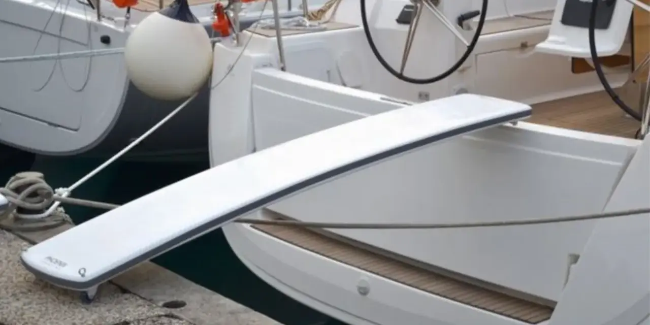 Eine selbstgebaute Gangway für Boote, die über eine Reling gelegt wird.