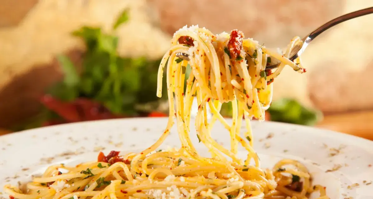 Widok z bliska na widelec z porcją spaghetti, posypane parmezanem i ziołami. Idealne jakie przyprawy do spaghetti!