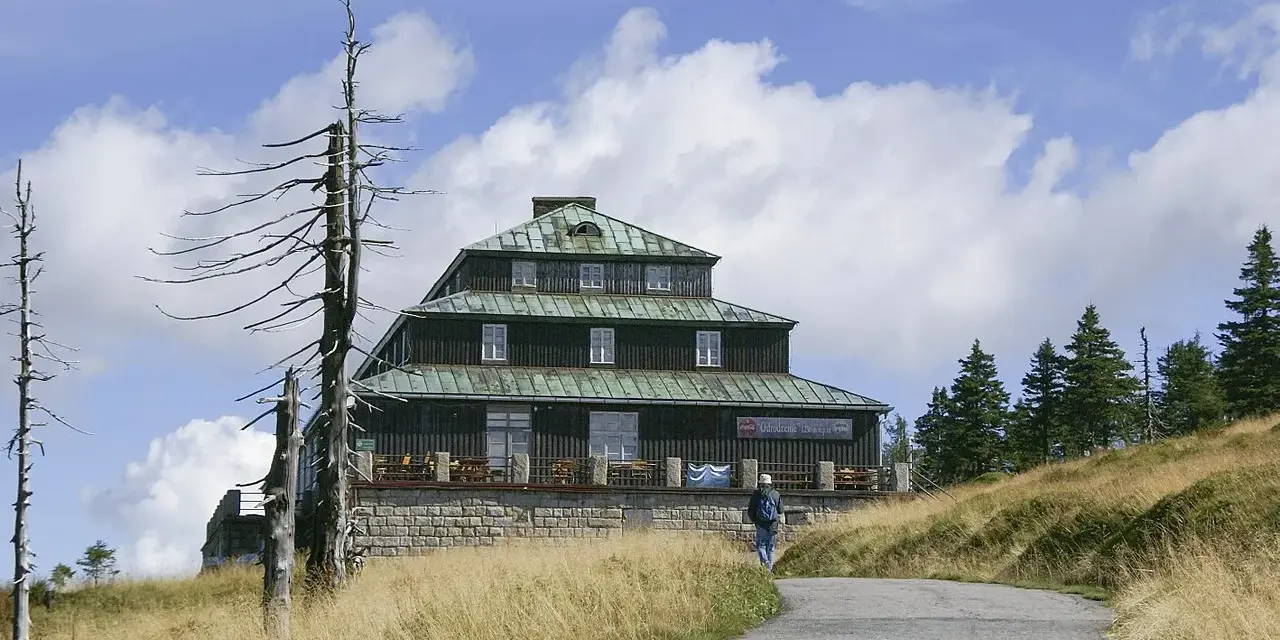 Schronisko Odrodzenie w Karkonoszach, z charakterystyczną architekturą i otoczone suchymi drzewami.