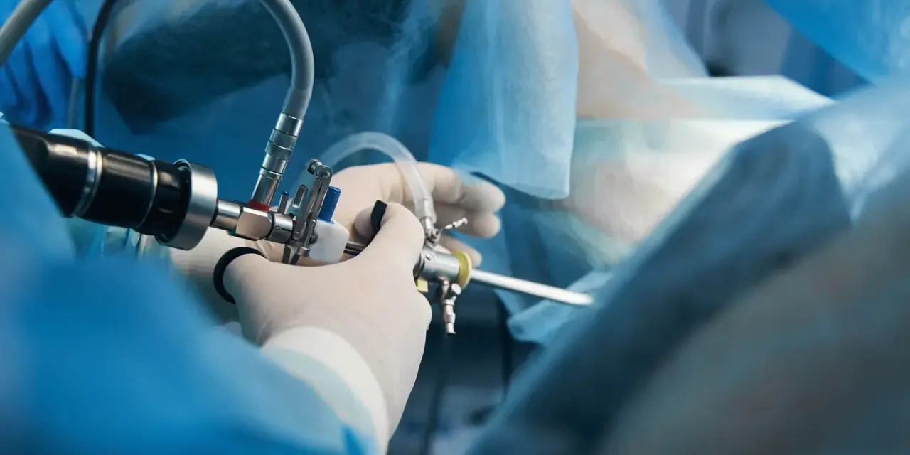 Chirurg w rękawiczkach używa histeroskopu. Po zabiegu kluczowe są zalecenia po histeroskopii operacyjnej.