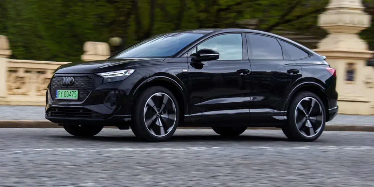Czarny Audi Q4 e-tron w ruchu. Sprawdź, jaki jest jego zasięg na jednym ładowaniu.